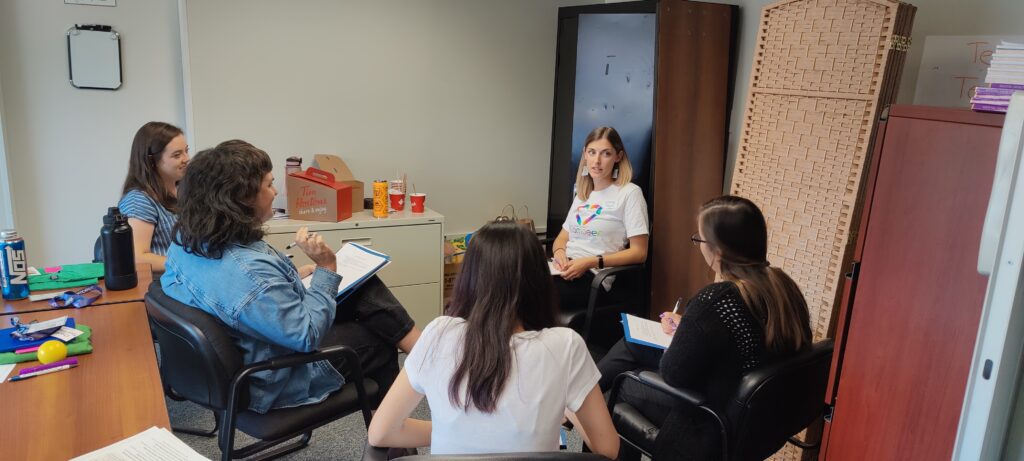 A Compeer staff member and a group of interns sitting in a circle talking.
