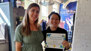 2 women smiling at camera with award in front of them